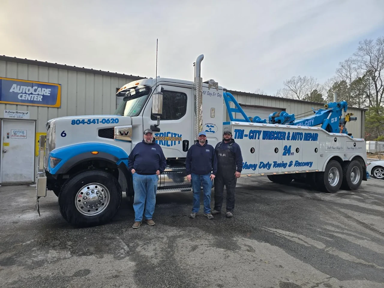 Pete, Kevin, and Timmy Lucy standing beside a Tri-City heavy-duty wrecker