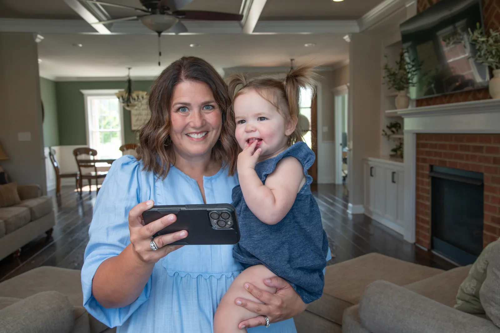 Parent holding a toddler while using mobile banking at home